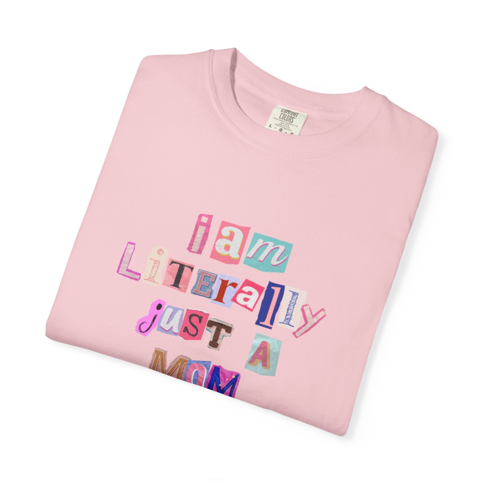 Folded pink t-shirt with colorful text "I am Literally Just a Mom" on a white background