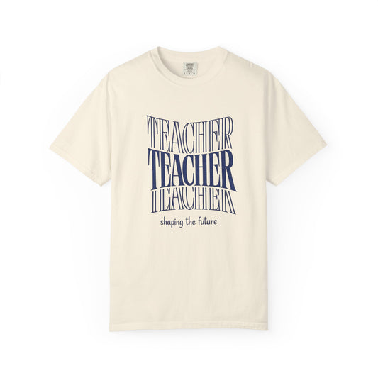Beige t-shirt with blue text "Teacher shaping the future" on a white background