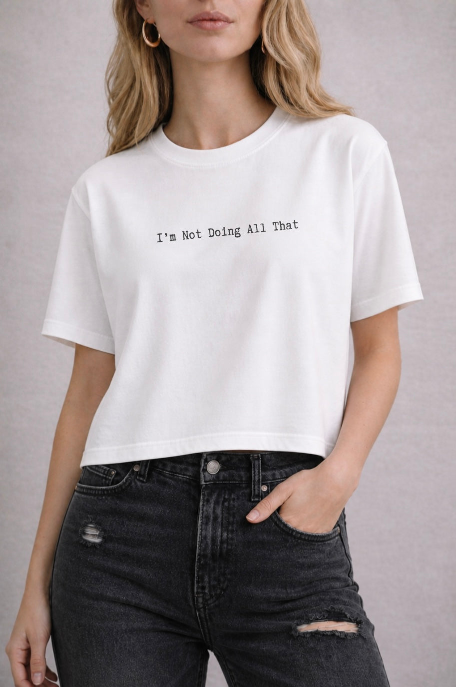 Person wearing a white t-shirt with text reading "I'm Not Doing All That" and black jeans on a plain background