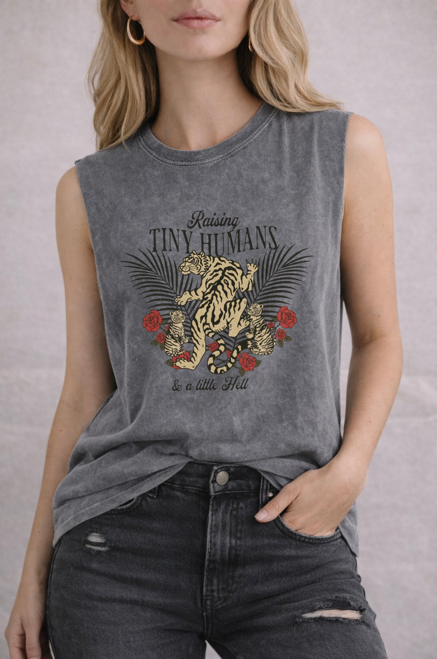 Woman wearing a sleeveless shirt with a tiger and floral design, text 'Raising Tiny Humans and a little hell'.