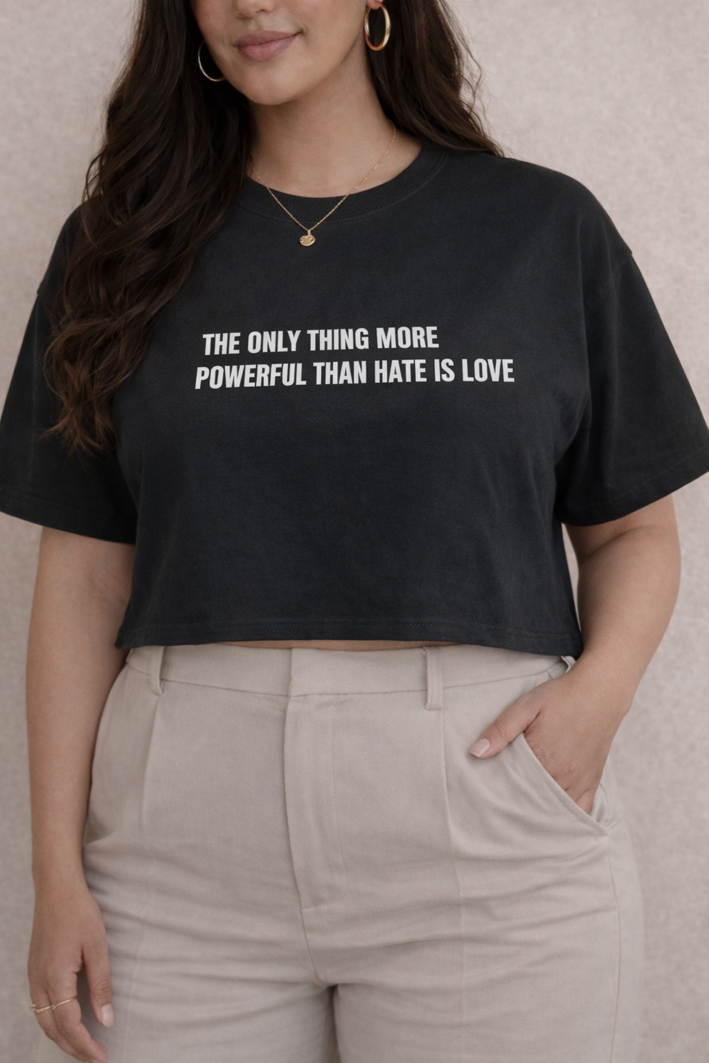 Person wearing a black t-shirt with a motivational quote "THE ONLY THING MORE POWERFUL THAN HATE IS LOVE" on a plain background