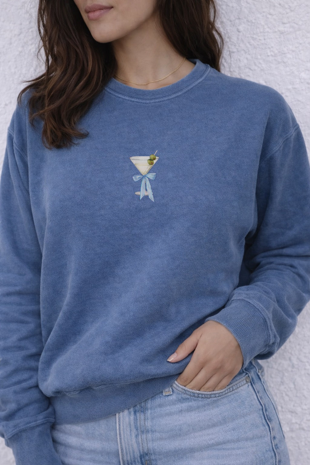 Person wearing a blue sweatshirt with a martini glass design against a white background
