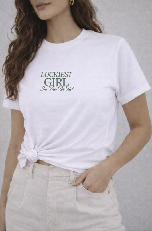 Woman wearing a white t-shirt with 'Luckiest Girl in the World' text on a plain background