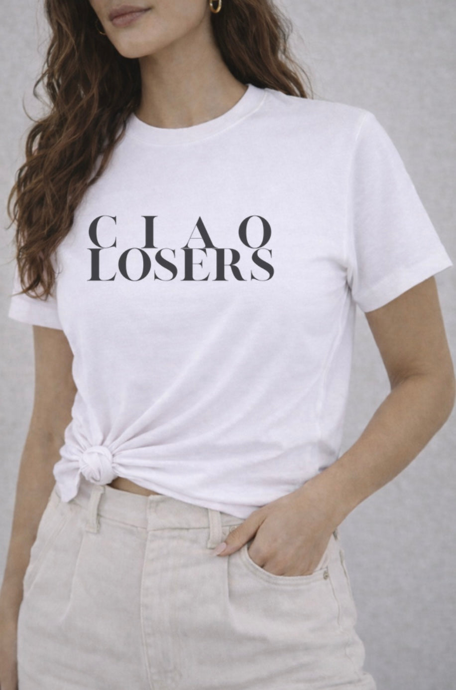 Person wearing a white t-shirt with 'CIAO LOSERS' text on a plain background