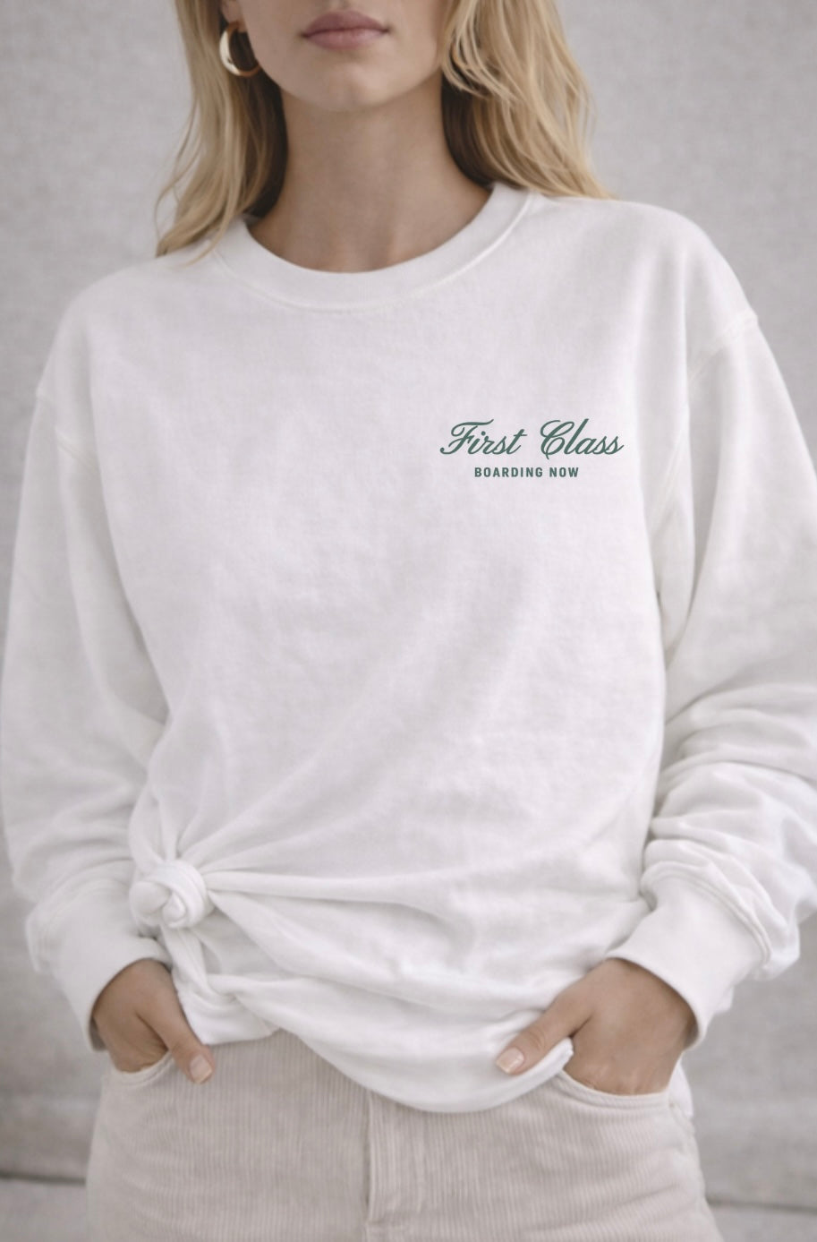 Person wearing a white sweatshirt with 'First Class Branding Now' text on a neutral background